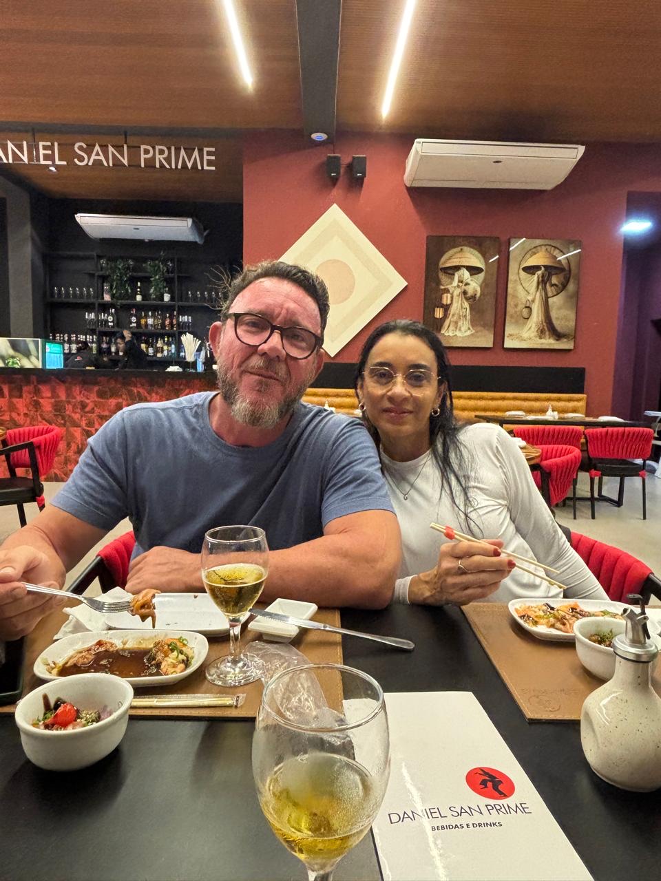 Dani e Giupira juntos num jantar, sorrindo para a foto.