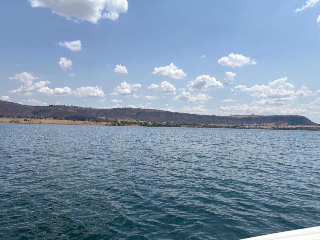 A represa vista de dentro do barco, morros ao fundo.