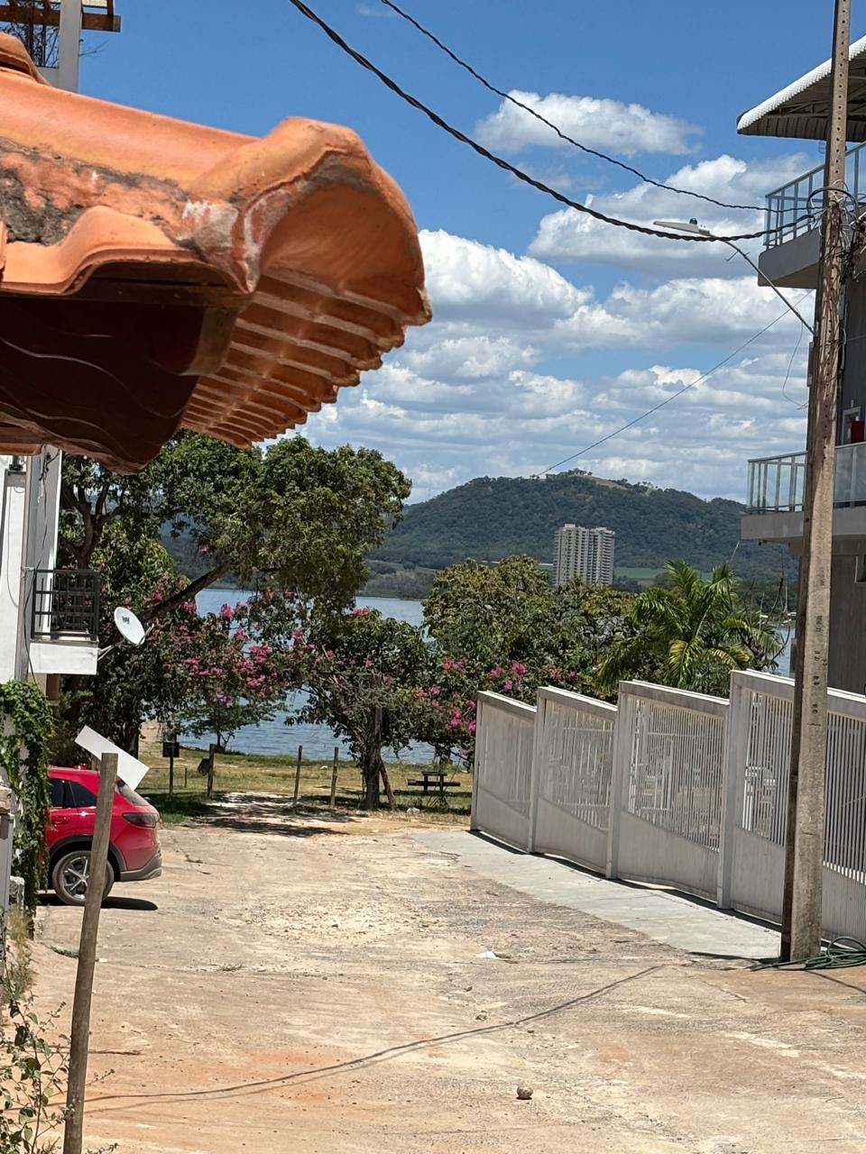 Rua de Rifaina com telha de barro e buganvília rosa, a represa ao fundo.